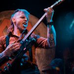 A man plays guitar with his tongue out on stage